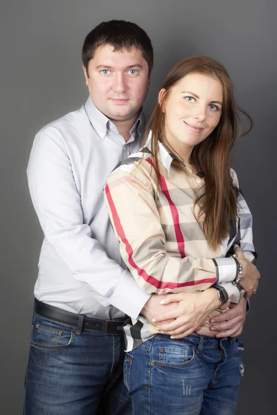 Retrato de una joven pareja sobre fondo gris . — Foto de Stock