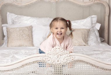 Çocuk yatağın üstüne oturuyor.