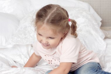 Çocuk yatağın üstüne oturuyor.