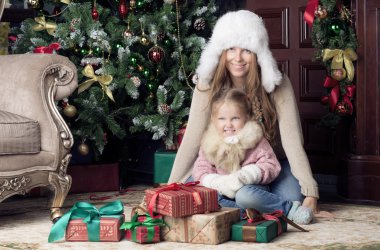 Kadın ve çocuk Noel ağacının yanında oturan.