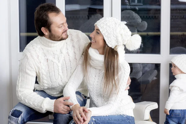 Familia vestida con suéteres blancos cerca de la ventana . — Foto de Stock