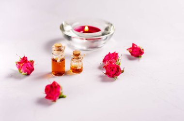 Spa terapisi, küçük gül çiçekleri, mum ve gri arka planda aromatik yağ.