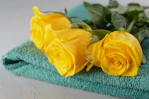 Üç sarı gül ve bir yeşil havlu. Spa konsepti, aromaterapi