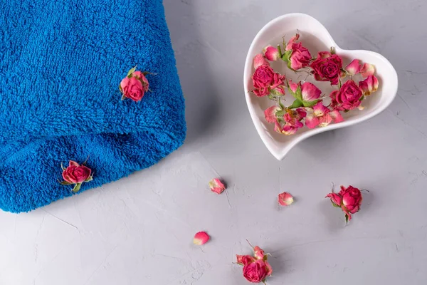 Çiçekler ve mavi havlu, gri arka plan. Spa terapisi, aromaterapi, dinlenme ve vücut bakımı