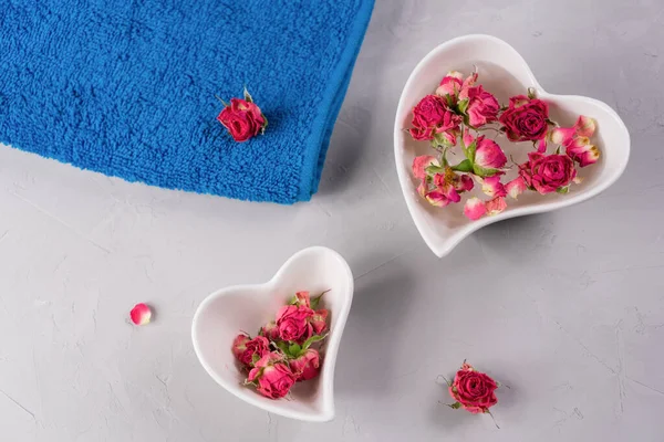 Çiçekler ve mavi havlu, gri arka plan. Spa terapisi, aromaterapi, dinlenme ve vücut bakımı