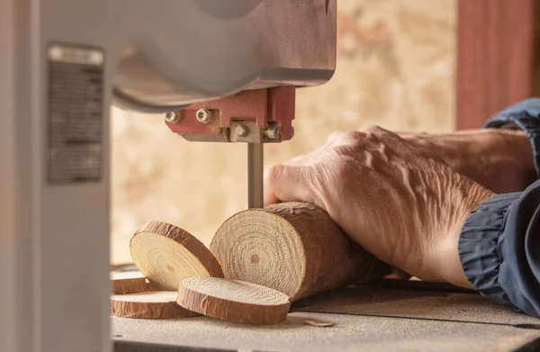 Carpenter works with wood on machine.