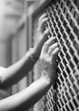 Siyah ve beyaz El Çelik tel çitlere tutunurken