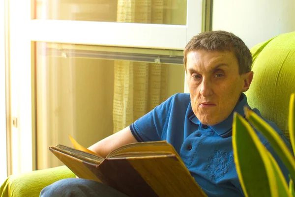 Un hombre con parálisis cerebral leyendo un libro . — Foto de Stock