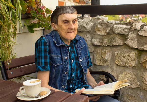 Un hombre con parálisis cerebral leyendo un libro . — Foto de Stock