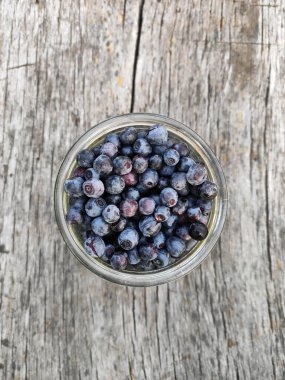 Ahşap bir arka planda yabanmersini. Cam kavanozda böğürtlen. Ahşap eski püskü arka plan. Masada yabanmersini var. Metin için Tahta Sınır Panoraması. Yaban mersini ağacı fotoğrafı..
