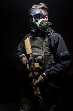 Kurşun geçirmez yelek ve saldırı tüfeği ile gaz maskeli adam.