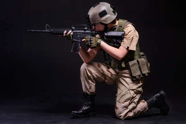 Chica en casco apuntando desde el rifle — Foto de Stock