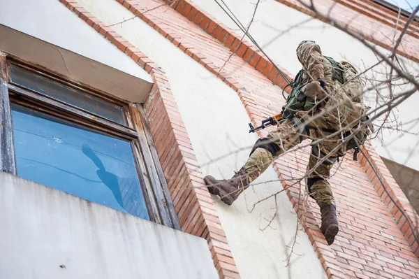 Military climber storm window of the building — Stockfoto