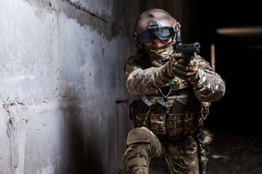 Silahını karanlık odada amaçlayan kamuflaj Ranger silahlı
