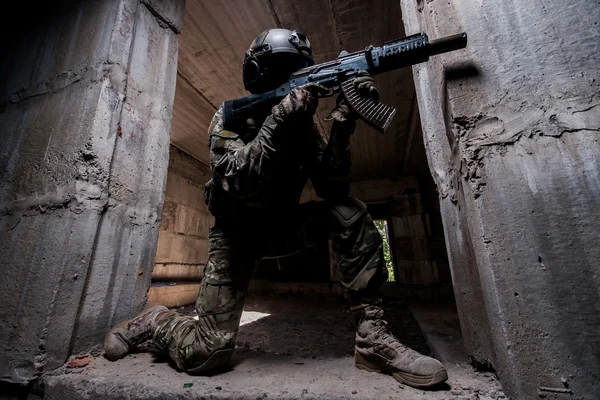 Soldado das forças especiais apontando um rifle no quarto escuro — Fotografia de Stock