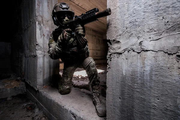 Armed ranger in in mask and helmet hiding in a building — Stock Photo, Image