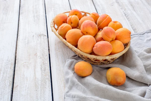 A basket of fresh apricots on vintage wooden table