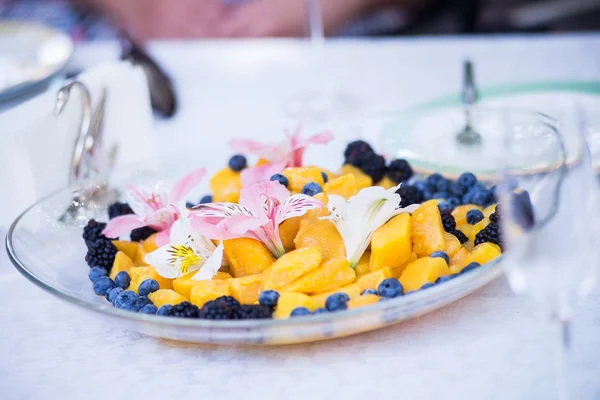 Tranches de mangue fraîche et de fleurs sur une assiette en verre — Photo