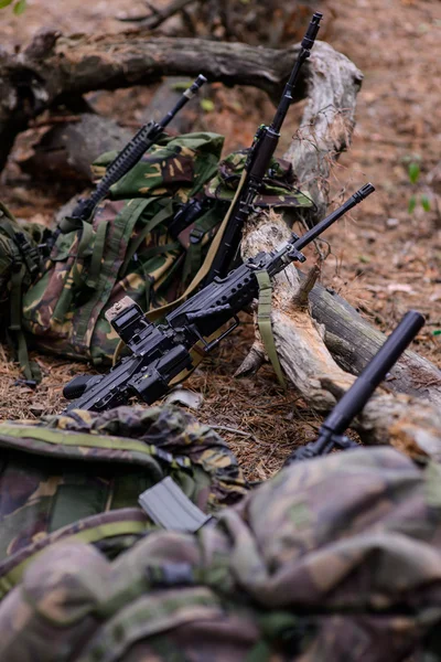 Кулемет, штурмові гвинтівки та камуфляжні рюкзаки в лісі — стокове фото