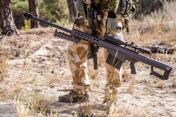 Солдат з великою снайперською гвинтівкою в лісі — стокове фото