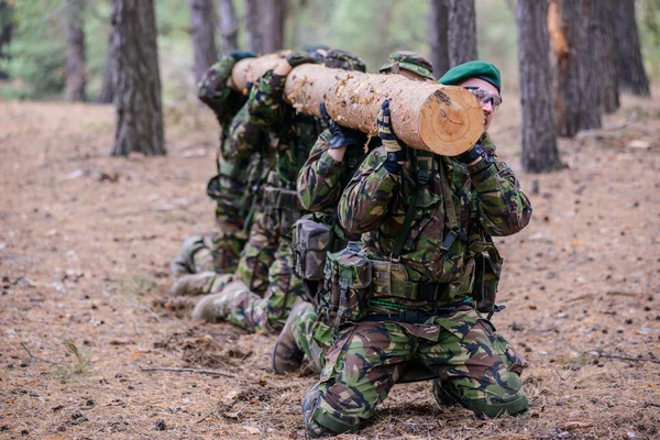 Soldater höll en logg på knä på utbildning — Stockfoto