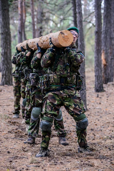 Groep soldaten in het forest die een grote log — Stockfoto