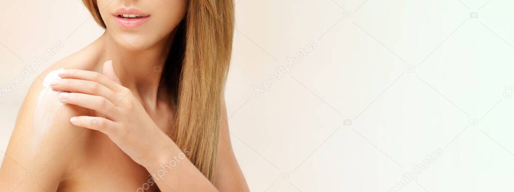 young blonde woman applying cream on shoulder