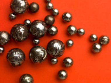 Kırmızı bir zemin üzerine yerleştirilmiş paslı eski bilye küreleri