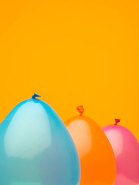 Koyu turuncu arka planda üç balondan yapılmış akuamarin, sarı ve turuncu bir portre.