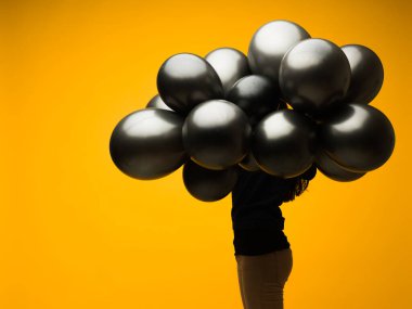 Kafasının önünde sarı arka planda siyah balonu olan genç bir kadın.