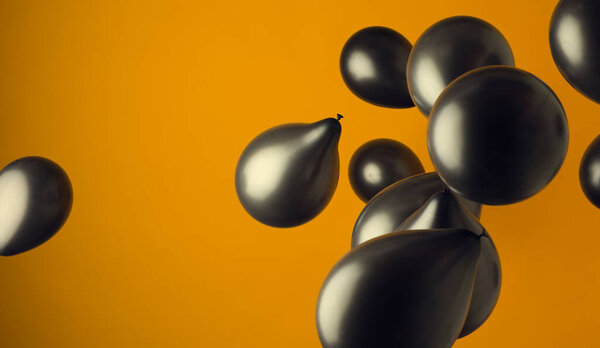 lanscape image of black ballons floting in front of a yellow background