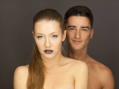 Stüdyo portresindeki güzel çift kameraya poz veriyor. Gülümsemenin arkasındaki adam.