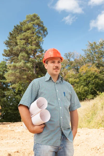 Sidebillede Stående Ingeniør Der Holder Tegninger Byggepladsen Udendørs - Stock-foto