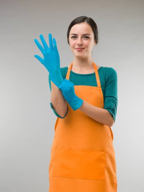 Genç mutlu temizlikçi kadın lastik eldiven takıyor.