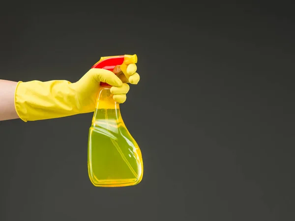 stock image hand with rubber glove holding cleaning spray bottle against grey background