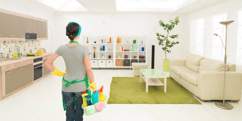 young caucasian woman standing in clean house holding cleaning products, looking at tidy room