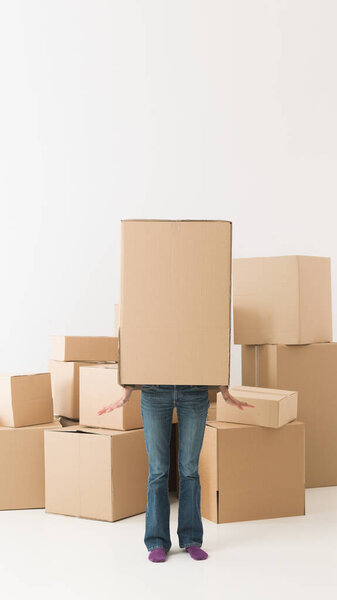 woman moving in new house, having fun hiding in cardboard box