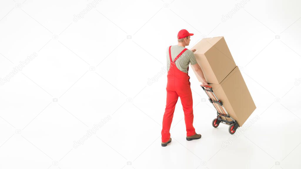 rear view of delivery man holding push cart loaded with cardboard boxes, on white background. copy space available