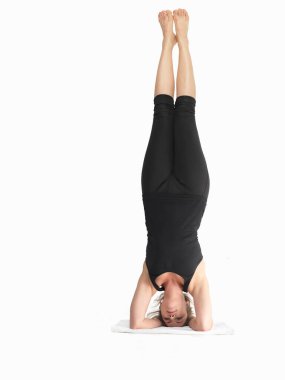 Siyah giyinmiş, beyaz arka planda, ileri yoga poziyonunda bekar genç bir bayana yakın durun. 