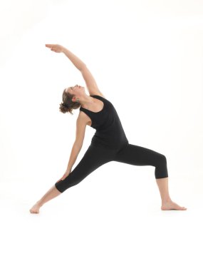 Sarışın, dengeli yoga pozu veren, beyaz arka planda siyah giyinen genç bir kadın.