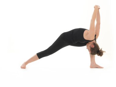 Yoga poziyonunda, siyah giyinmiş, beyaz arka planda, gözleri kapalı genç bir kadın.