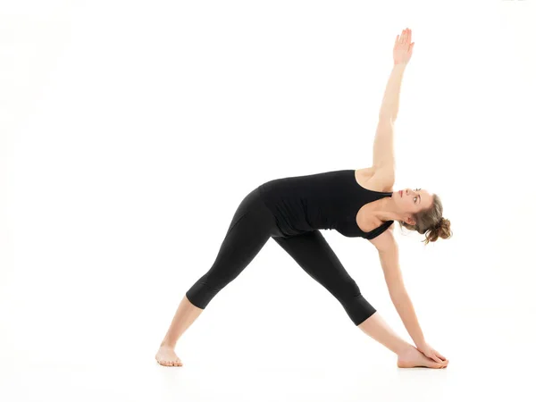 Gelişmiş yoga duruşu, bloden kız tarafından gösterilmiş, siyah giyinmiş, beyaz arka planda.