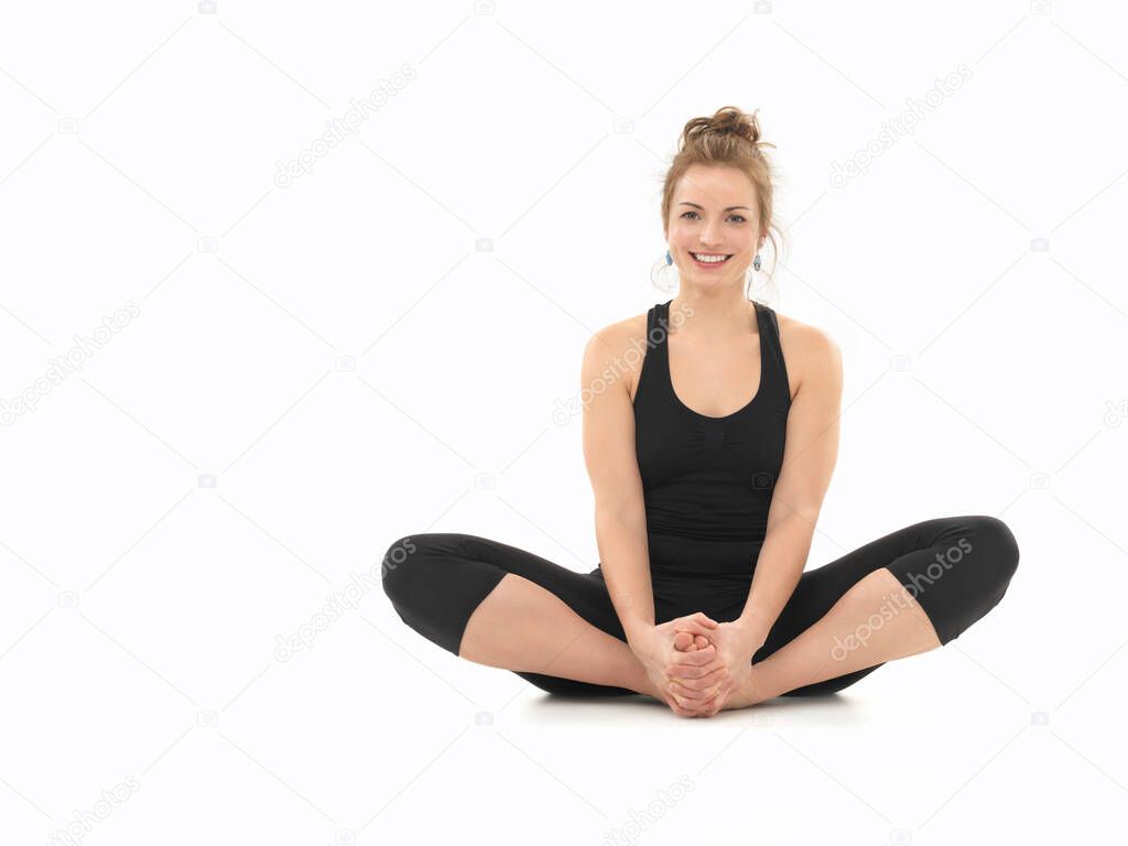 young girl smiling, demonstrating yoga pose, full front view, dressed in black, on white background