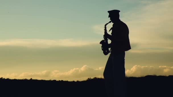 Saxofonist. man spelar på saxofon mot bakgrund av solnedgången — Stockvideo