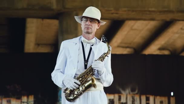 Saxofonista con sombrero blanco y bata blanca con saxofón en las manos . — Vídeos de Stock