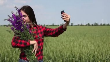 Genç kadın esmer kır çiçekleri bir buket selfie yapar.