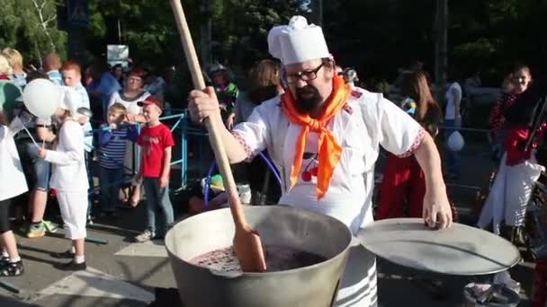 Festival "Cherry 2016". Melitopol. Ucrânia. Chef masculino distribui as crianças da caldeira para aquecer as cerejas de geleia. 10 de junho de 2016 — Vídeo de Stock