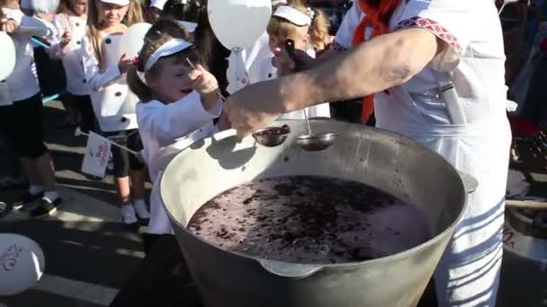 Fesztivál "Cherry 2016". Melitopol. Ukrajna. Férfi szakács osztja el a gyermek a kazán a hő a lekvár cseresznye. 2016. június 10. — Stock videók