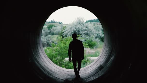 Silhouet van een jonge man die het naderen van de camera op de achtergrond van een enorm gat. — Stockvideo