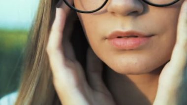 Gözlüklü genç bir kadın. Yüz, dudaklar yakın çekimler. Film olarak stilize. Odağı bulanıklık.